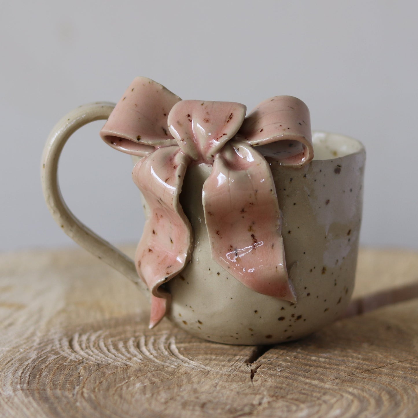 Cremefarvet kop med hank og sløjfe